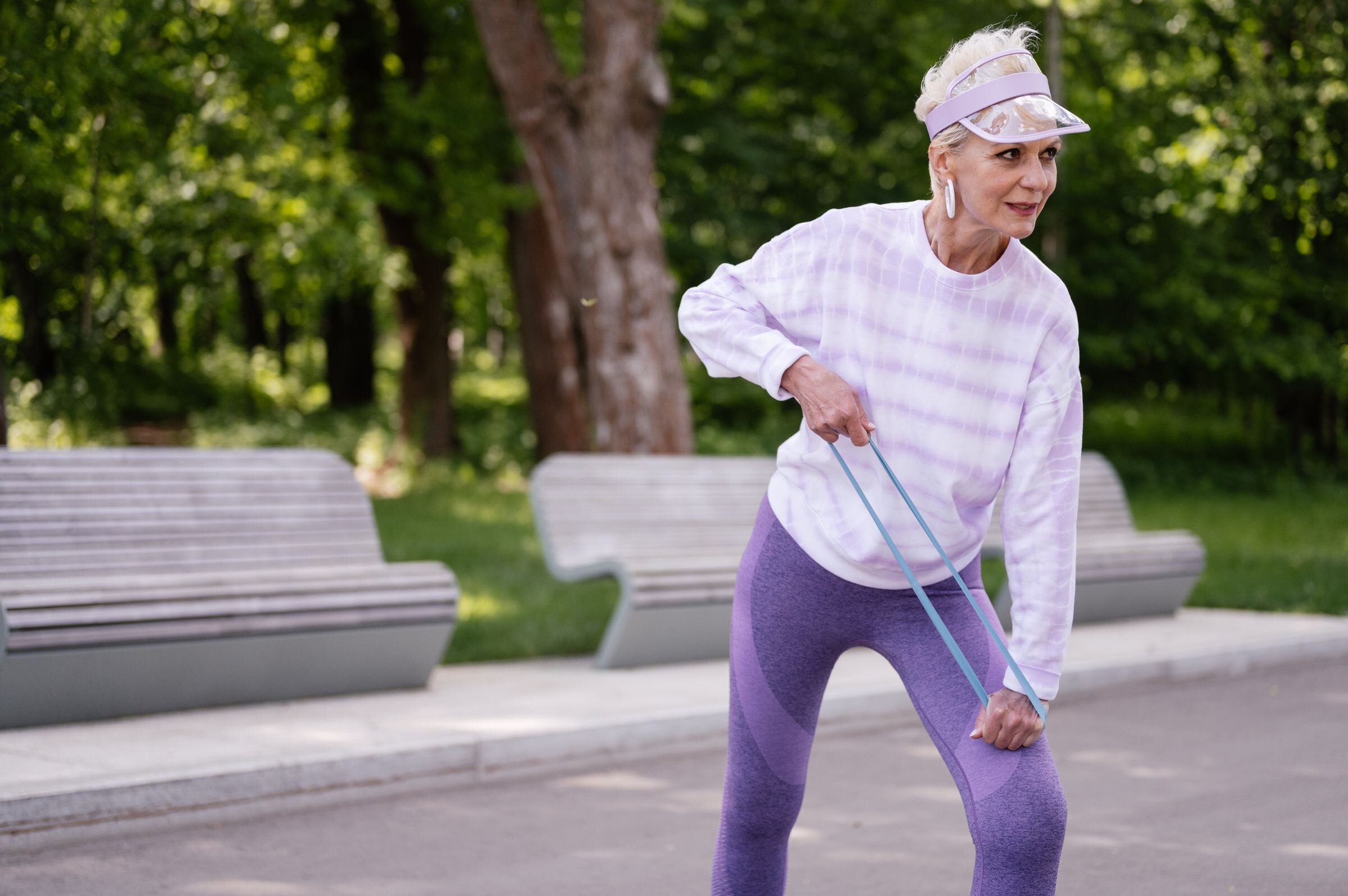 An older woman exercising with a resistance band in a park